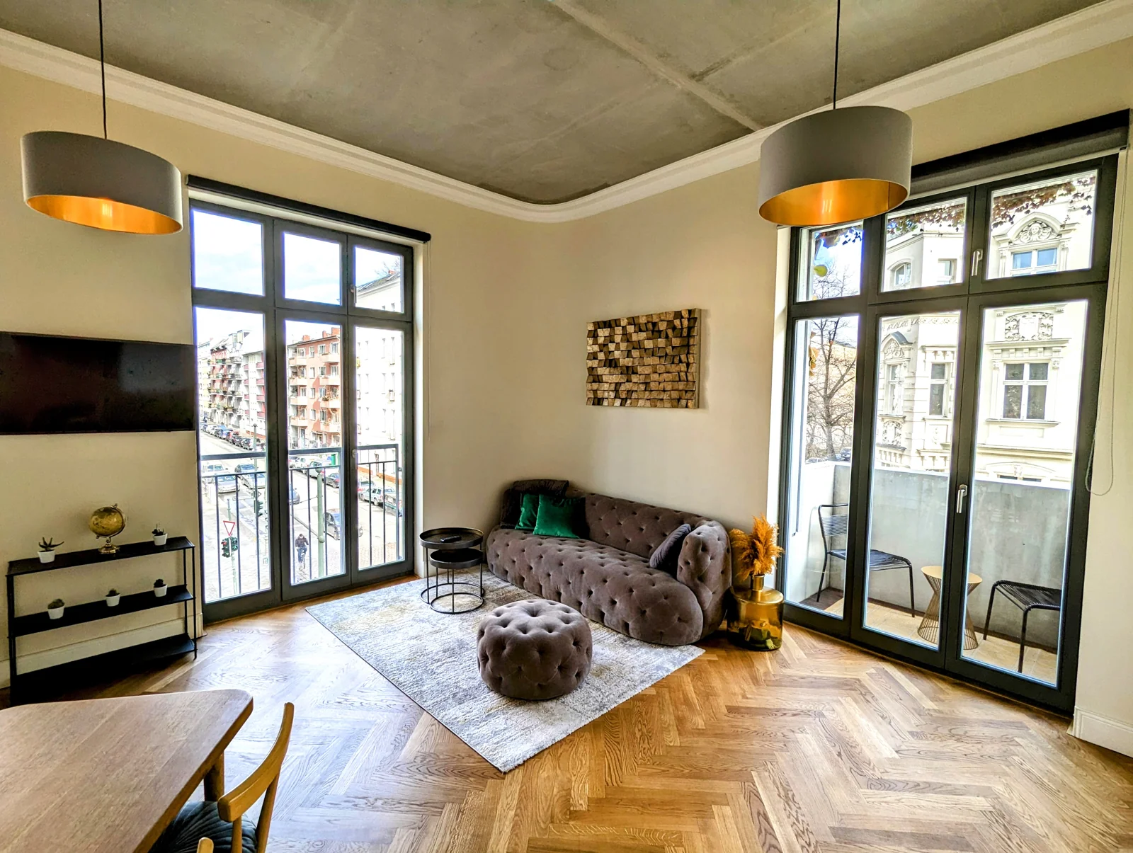 Sunlit living room with tall windows, a velvet sofa and warm wooden floors